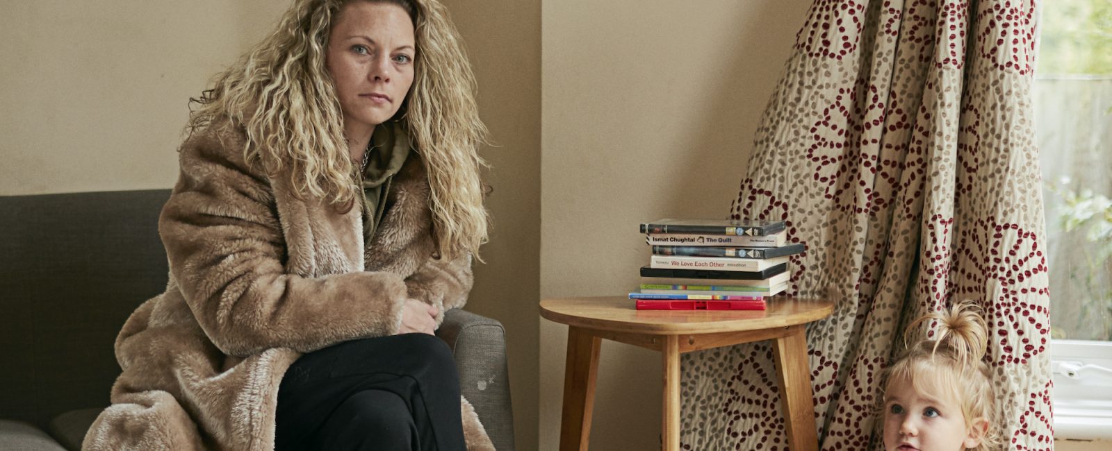 Lindsey and Ellie sitting in their bare living room, that they have tried to make a home