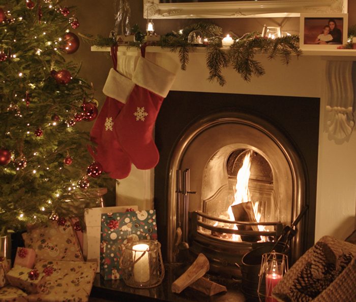 A fie place lit with christmas decorations around it