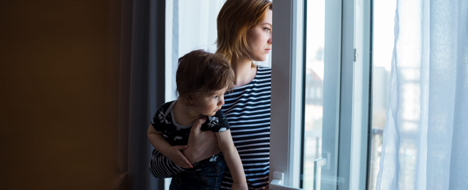 woman staring out of window with child