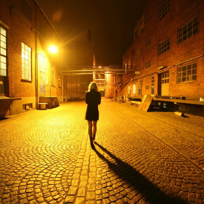 Woman walking at night under street lamps